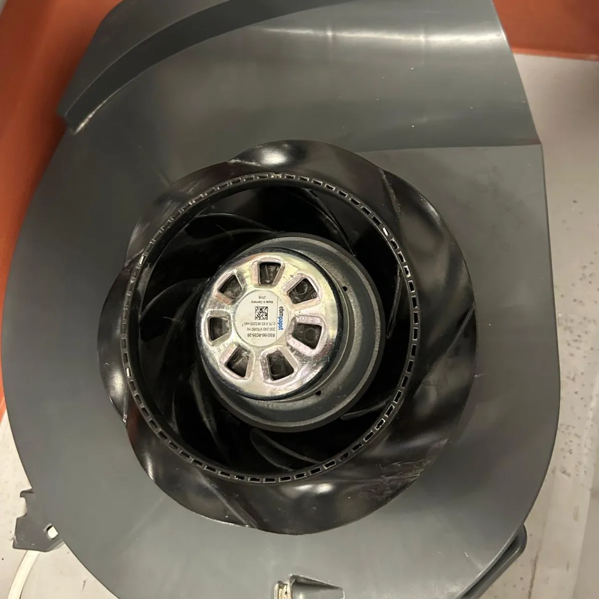 The same impeller after cleaning, black blades clean and the motor visible in the centre.