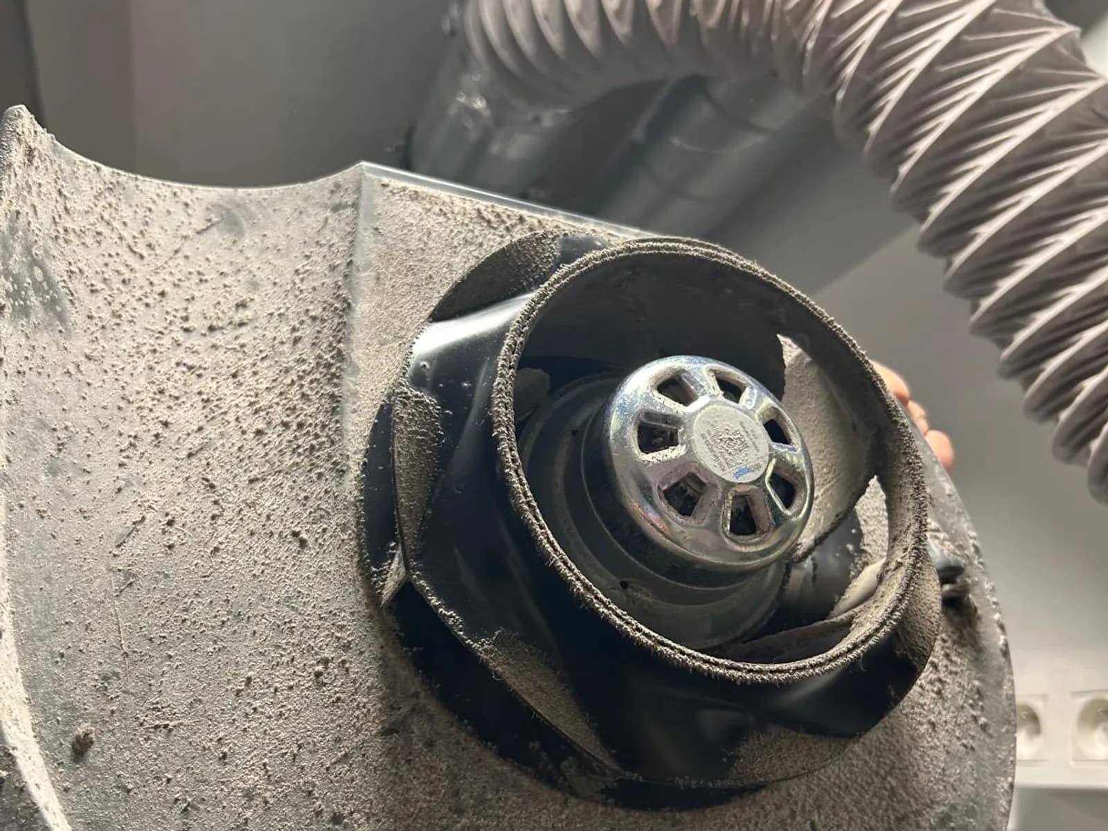Turbine de ventilateur déposée lors d'un dépannage, pales et volute couvertes d'une épaisse couche de poussière.