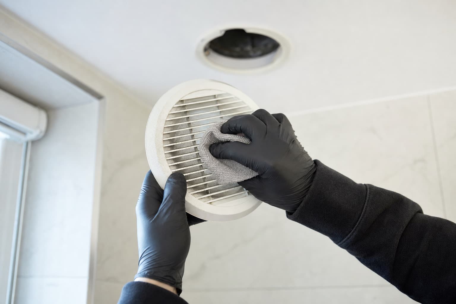 Bouche d'extraction de salle de bain déposée et nettoyée à sec pendant l'entretien d'une VMC simple flux.