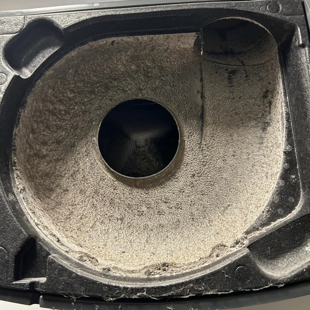 Volute de ventilateur ouverte avant nettoyage, parois tapissées d'une épaisse couche de poussière feutrée.